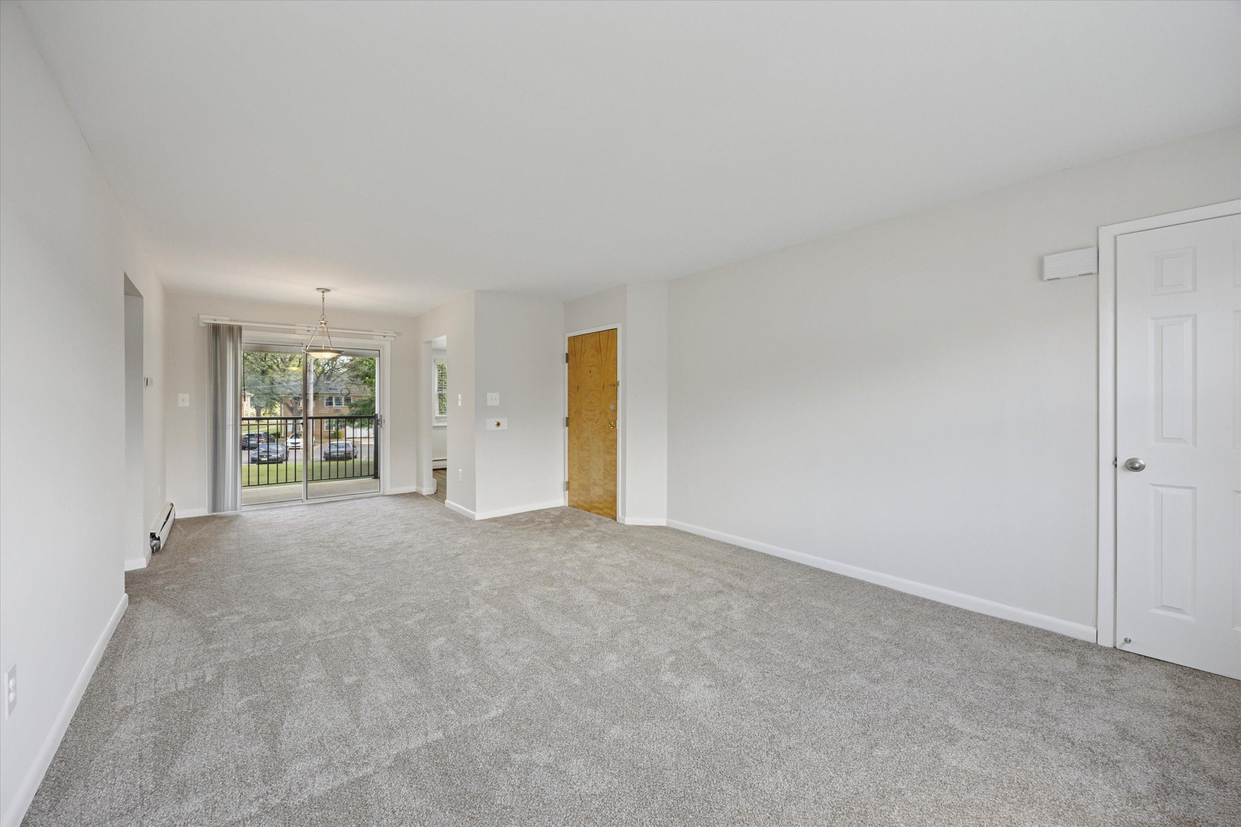 A large empty room with a carpeted floor and white walls.
